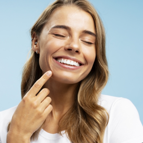Smiling woman points finger at teeth